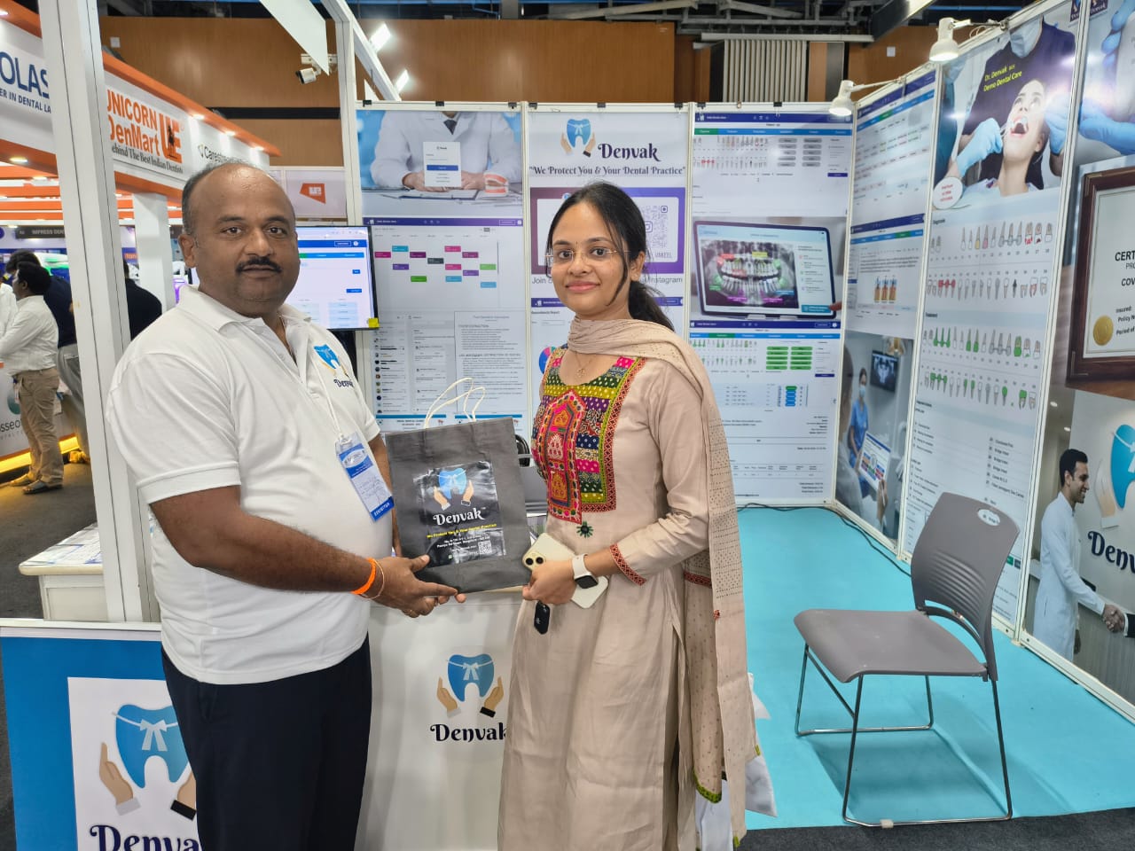 Denvak team member presenting a delegate kit at Expodent Chennai 2026